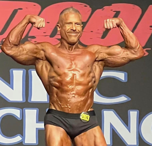 Dr. Cabrera on stage displaying muscle definition at a bodybuilding competition
